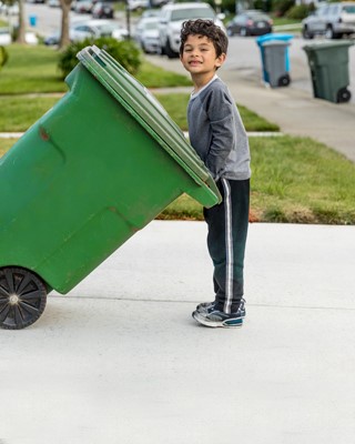 Young boy pulling a garbage can