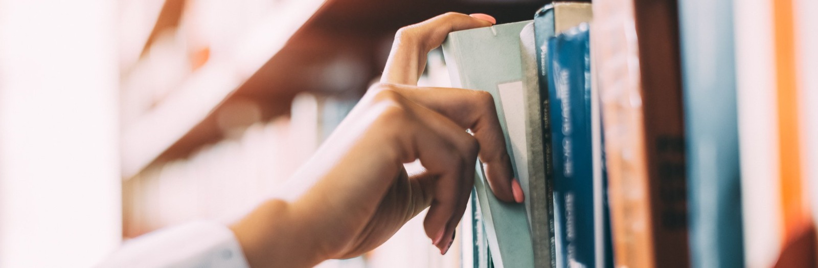 Person taking a book from a bookshelf