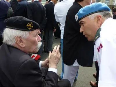 Le vétéran Michel Doiron de la délégation de Dieppe discute avec un vétéran français / Veteran Michel Doiron from the Dieppe delegation discusses with a French veteran.